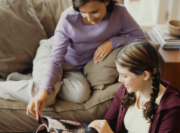 Mother and daughter (16-17) reading magazine